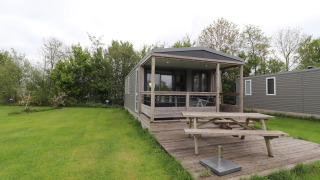 Terrace Lodge 2 avec terrasse couverte, table de pique-nique et pelouse, entouré de verdure et d’arbres.
