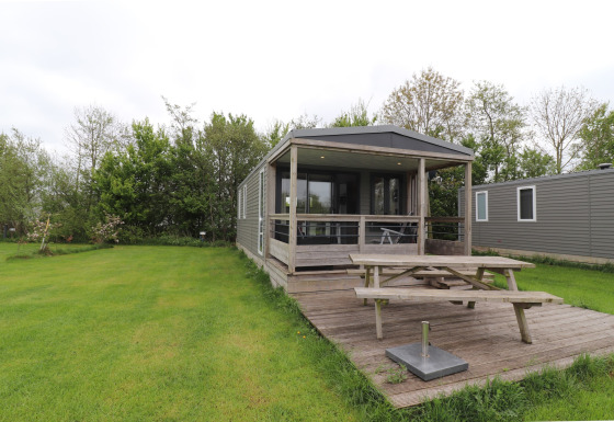 Terrace Lodge 2 features a covered porch, picnic table, and lush lawn surrounded by greenery and trees.