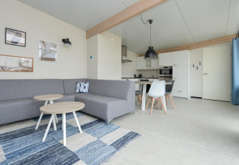 Modernes Wohnzimmer und KĂĽche im Sea Lodges Bloemendaal 4 Strandhaus in den Niederlanden, graues Sofa.