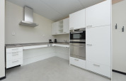 Modernes weißes Kücheninterieur mit Einbaugeräten in einem Strandhaus an der holländischen Küste.
