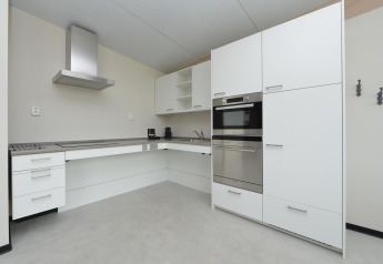 Modernes weißes Kücheninterieur mit Einbaugeräten in einem Strandhaus an der holländischen Küste.