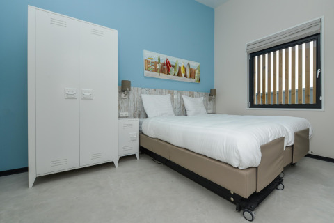 Moderne slaapkamer bij Sea Lodges 'Bloemendaal 4' in Nederland met twee bedden, kast en blauwe muur.