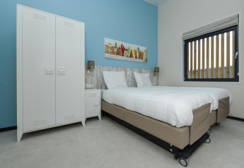 Modernes Schlafzimmer in Sea Lodges 'Bloemendaal 4', Niederlande, mit weiĂźen Betten, Schrank und Fenster.