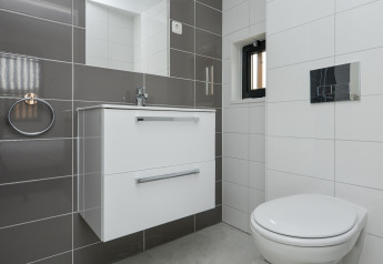 Modernes Badezimmer in den Sea Lodges „Bloemendaal 4“ in den Niederlanden mit weiß-grauen Fliesen.