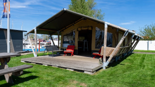 Safari-Zelt Heeg für 4 Personen mit Terrasse, Liegestühlen und Blick auf den Jachthafen im Freien.