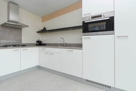 Moderne hoekkeuken in Sea Lodges «Bloemendaal 3» in Nederland, met witte kasten en ingebouwde oven.
