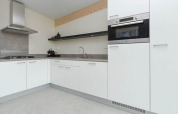 Cuisine moderne en angle aux Sea Lodges «Bloemendaal 3» aux Pays-Bas, avec placards blancs et four intégré.