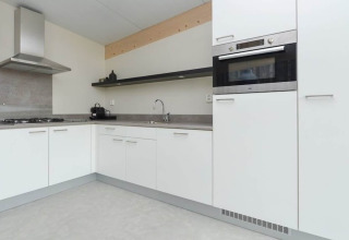 Cocina moderna en esquina en Sea Lodges «Bloemendaal 3», Países Bajos, con gabinetes blancos y horno.