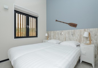 Chambre claire avec deux lits simples, une fenêtre et une décoration de rame murale à Sea Lodges Bloemendaal.