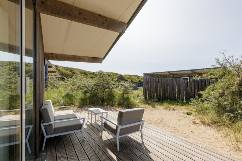 Buitenterras met moderne tuinmeubels bij Sea Lodges Bloemendaal 3 in Nederland, omgeven door natuur.