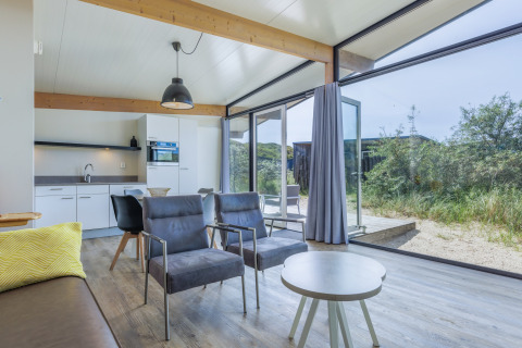 Sala de estar moderna en Sea Lodges «Bloemendaal 3» en Holanda con grandes ventanales y vistas naturales.