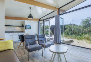 Moderne leefruimte in Sea Lodges «Bloemendaal 3» in Nederland met grote ramen en zicht op de natuur.