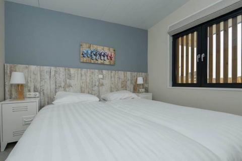 Dormitorio moderno en Sea Lodges «Bloemendaal 3», Países Bajos, con dos camas, mesitas y ventana grande.