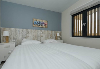Moderne slaapkamer in Sea Lodges «Bloemendaal 3» met twee aparte bedden, nachtkastjes en groot raam.