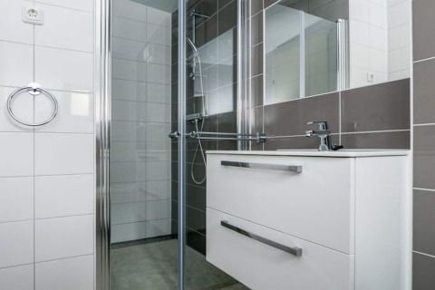 Moderne badkamer in Sea Lodges Bloemendaal 3, Nederland, met douche en wit badkamermeubel.