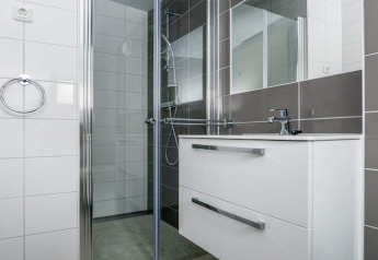 Salle de bain moderne aux Sea Lodges Bloemendaal 3, Pays-Bas, avec douche et meuble-lavabo blanc.