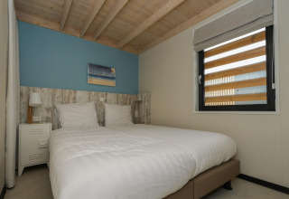 Slaapkamer in strandhuis Sea Lodges Bloemendaal 2 in Nederland met houten plafond en dubbel bed.