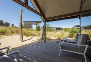 Uitzicht vanop het terras bij Sea Lodges Bloemendaal 2 in Nederland met hangmat en moderne zetels.