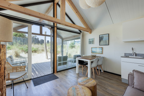 Lichte, moderne woonkamer van Sea Lodges Bloemendaal 2 met grote ramen en uitzicht op de duinen in Nederland.