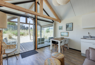 Lichte, moderne woonkamer van Sea Lodges Bloemendaal 2 met grote ramen en uitzicht op de duinen in Nederland.