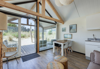 Helles, modernes Wohnzimmer der Sea Lodges Bloemendaal 2 mit groĂźen Fenstern und DĂĽnenblick in den Niederlanden.