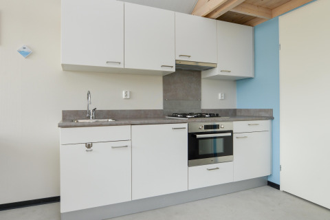 Moderne keuken met witte kasten, oven, kookplaat en spoelbak in een vakantiewoning aan zee.