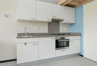 Moderne keuken met witte kasten, oven, kookplaat en spoelbak in een vakantiewoning aan zee.