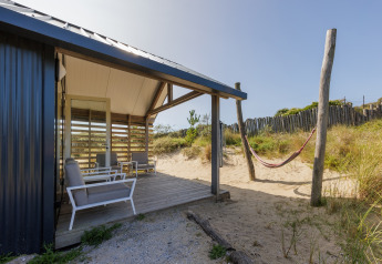 Strandhaus mit überdachter Terrasse, Sitzgelegenheiten und Hängematte bei Sea Lodges Bloemendaal, Niederlande.