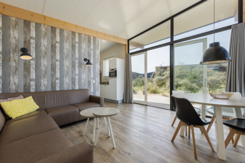 Sala moderna en Sea Lodges Bloemendaal 1, Países Bajos, con ventanales y decoración elegante y luminosa.