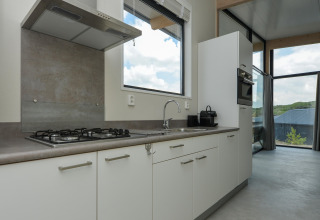 Moderne keuken met gasvuur, gootsteen en grote ramen bij Sea Lodges Bloemendaal 1, Nederland.