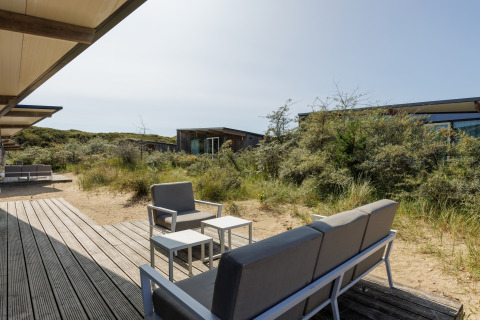 Buiten zitruimte met moderne meubels bij Sea Lodges Bloemendaal 1, omringd door duinen in Nederland.