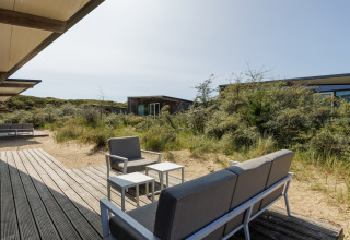 Buiten zitruimte met moderne meubels bij Sea Lodges Bloemendaal 1, omringd door duinen in Nederland.