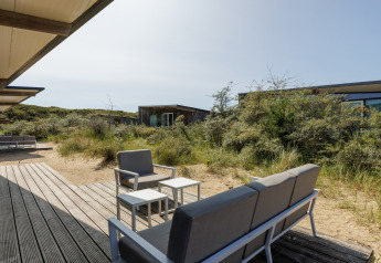 Coin salon extérieur avec mobilier moderne à Sea Lodges Bloemendaal 1, entouré de dunes aux Pays-Bas.
