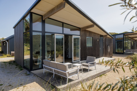 Moderne lodge Sea Lodges 'Bloemendaal 1' in Nederland, met grote ramen en een buitenterras met zithoek.