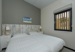 Moderne slaapkamer met twee eenpersoonsbedden, nachtkastjes en lampen in Sea Lodges Bloemendaal 1, Nederland.