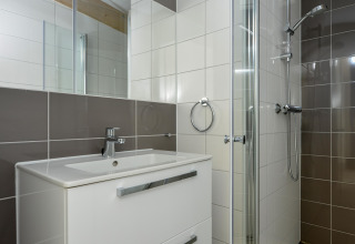 Moderne badkamer met douche, wastafel en spiegel in Sea Lodges «Bloemendaal 1» in Nederland.