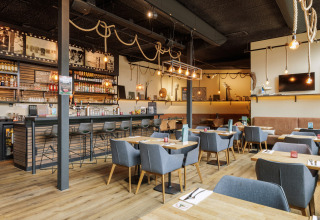 Modern restaurant en barinrichting bij Sea Lodges Bloemendaal 2 in Nederland, met knusse verlichting en stoelen.