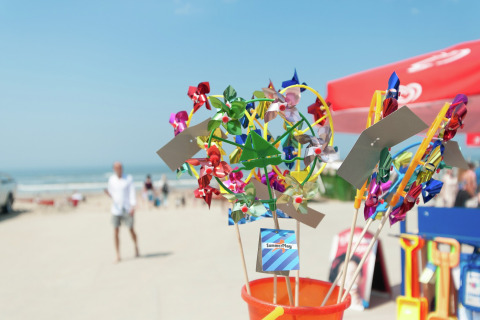 Kleurrijke windmolentjes in een emmer op het strand bij Sea Lodges Bloemendaal, Nederland, op een zonnige dag.