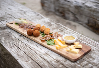 Charcuterieplank met kaas, salami en dipsaus op een rustieke tafel bij Sea Lodges Bloemendaal, Nederland.
