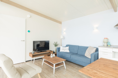 Heldere woonkamer in Sea Lodges Ameland 4, Nederland, met blauwe zetel en eigentijdse stijl.