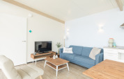 Sala luminosa en Sea Lodges Ameland 4, Países Bajos, con sofá azul y decoración contemporánea.