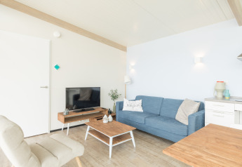 Sala luminosa en Sea Lodges Ameland 4, Países Bajos, con sofá azul y decoración contemporánea.