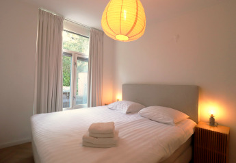 Schlafzimmer der Wellness Suite Lodge in den Niederlanden mit Doppelbett, Lampen und Fenster.