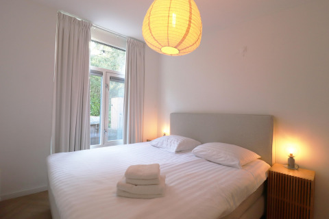Soveværelse i Wellness suite-lodgen i Holland med dobbeltseng, natborde og store vinduer.