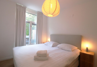 Soveværelse i Wellness suite-lodgen i Holland med dobbeltseng, natborde og store vinduer.