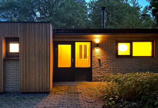 Udendørs aftenbillede af Wellnes suite lodge i Holland med varme lys indefra og grønne omgivelser.