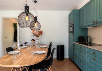 Moderne Küche und Essbereich in der Wellness Suite in den Niederlanden mit Holztisch und blauen Schränken.