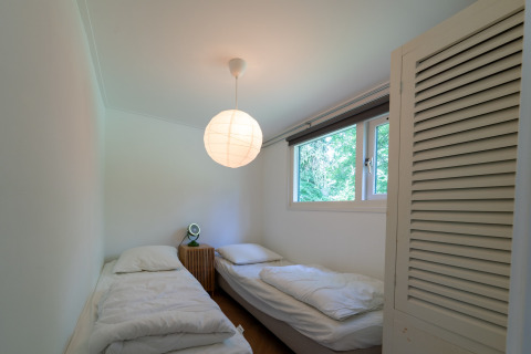 Soveværelse med to enkeltsenge, natbord og stort vindue på Wellness suite lodge i Holland.