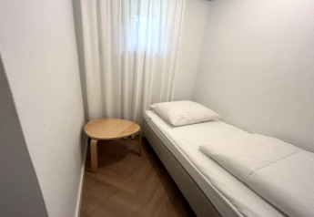 Ein schlichtes Zimmer in der Wellnes suite in den Niederlanden mit Bett, weißer Bettwäsche und Beistelltisch.