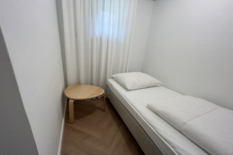 Et minimalistisk værelse hos Wellnes suite i Holland med en seng, hvidt sengetøj og et lille rundt bord.